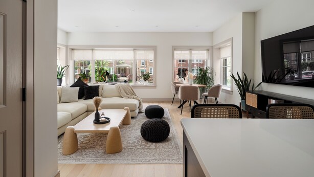 Un salon moderne avec un canapé, une table basse, des poufs et un téléviseur.