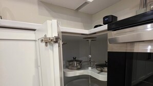 Kompakti keittiö, jossa on valkoiset kaapit, sisäänrakennettu uuni ja mikroaaltouuni.