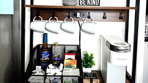 En kaffestation med en Keurig-maskine, et skilt der siger 'Kaffe er min sande kærlighed', og et 'Vær venlig' skilt på en hylde.