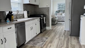 Et moderne køkken med hvide skabe, et rustfrit stål køleskab og en backsplash i grå fliser.
