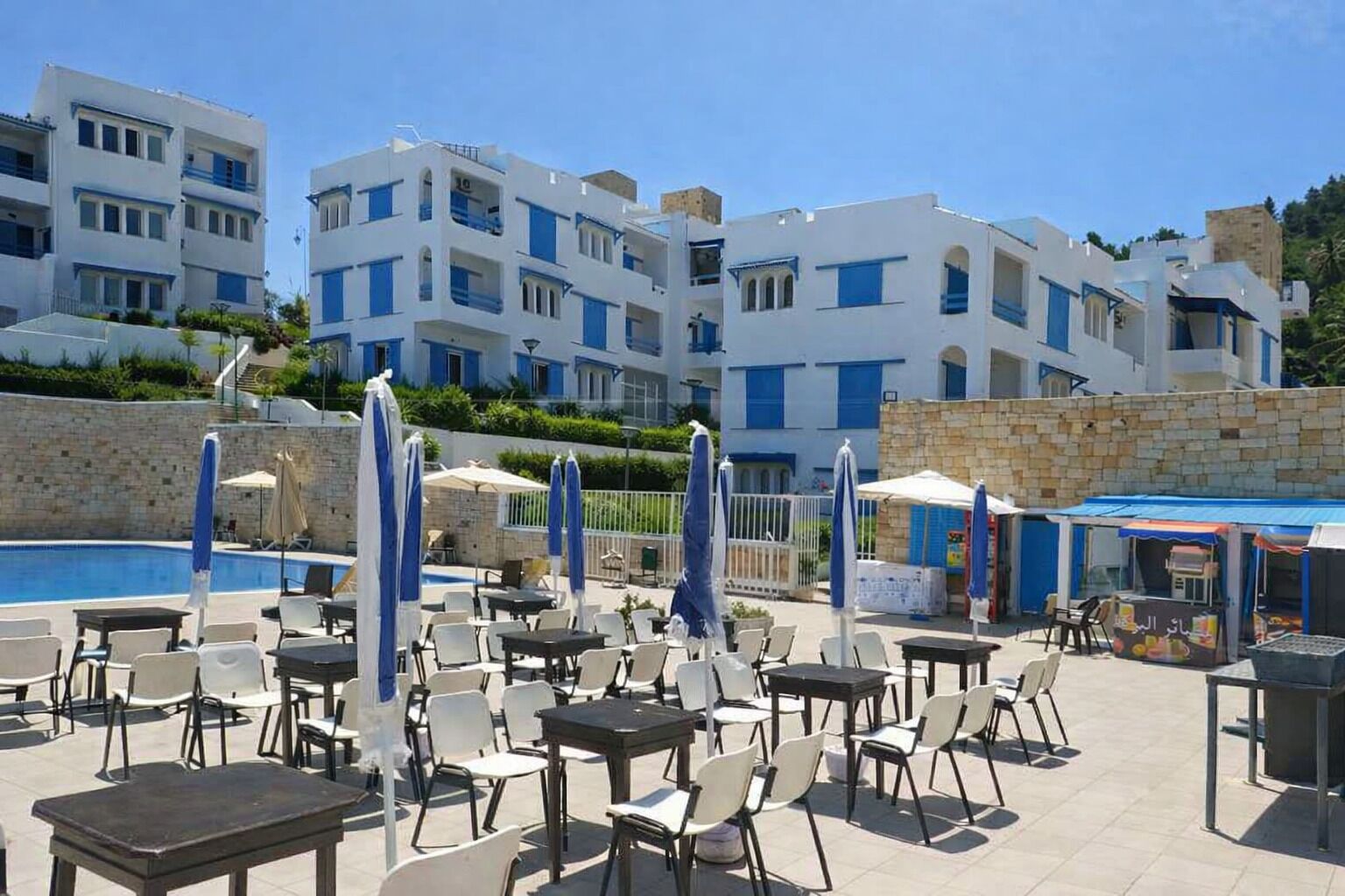 A hotel with a pool area, outdoor seating, and multiple-story buildings.