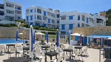 A hotel with a pool area, outdoor seating, and multiple-story buildings.