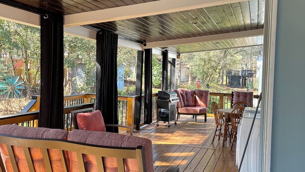 Un espace extérieur abrité, doté d’un plancher en bois, de sièges rembourrés et d’un barbecue.