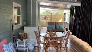 Une terrasse couverte avec une table et des chaises en bois, un radiateur blanc et un banc rembourré.