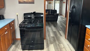 Une cuisine équipée d’une cuisinière, d’un réfrigérateur et de meubles de rangement en bois.