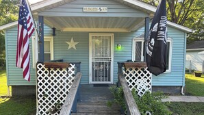 Une maison avec un porche, une décoration en forme d’étoile et un drapeau.