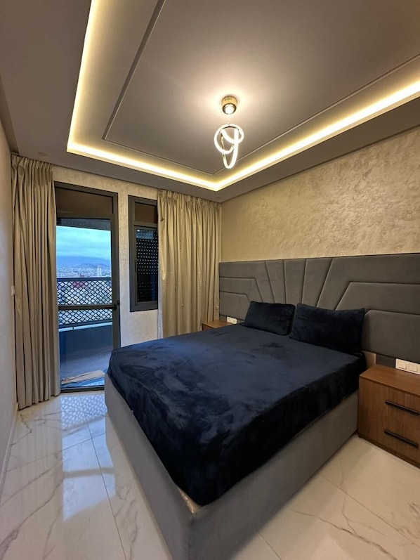A modern bedroom with a large bed, a nightstand, and a ceiling light fixture. - Azure Nador Suites (Nador)