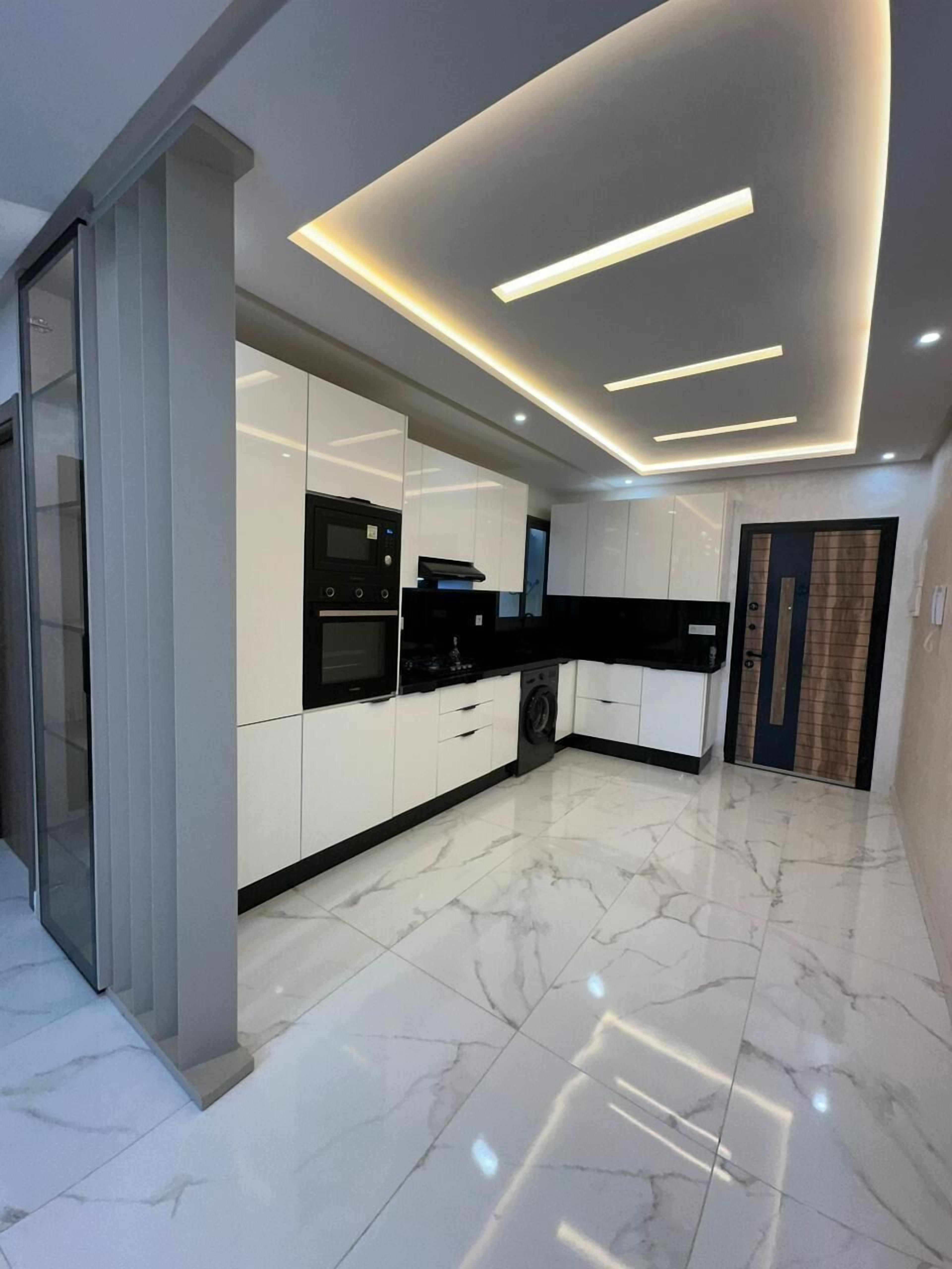 A modern kitchen with white cabinets, a black countertop, and a built-in oven.