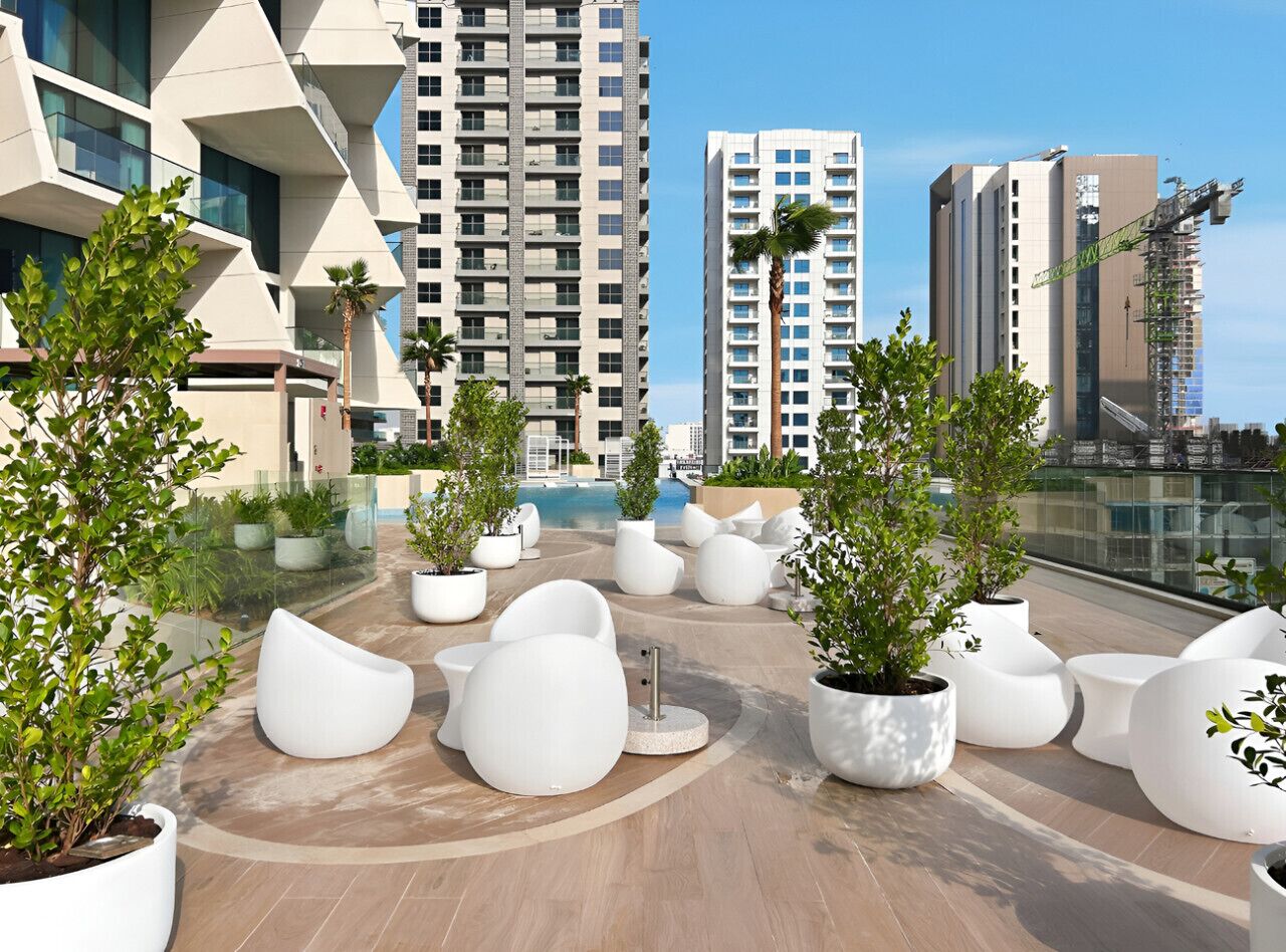Une terrasse sur le toit, aménagée avec des meubles modernes, des plantes en pot et offrant une vue sur les immeubles environnants.