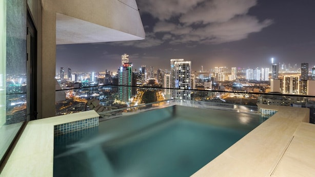 Una piscina infinita en la azotea con vistas al horizonte urbano.