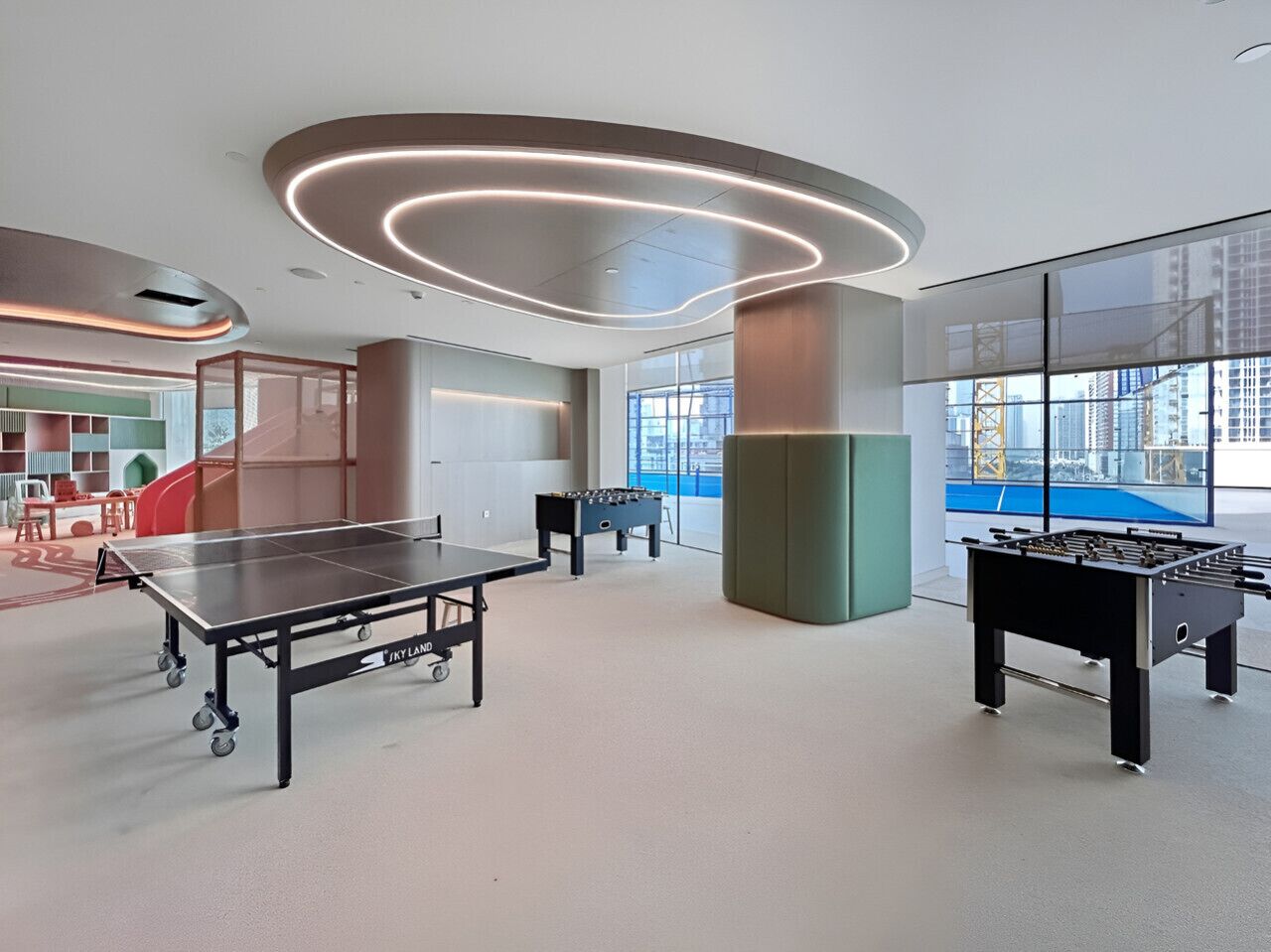 A modern indoor recreational area with a foosball table, ping pong table, and a foosball table in the background.