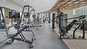 Un gimnasio moderno con diversos equipos de ejercicio, ventanas amplias y un diseño limpio y espacioso.