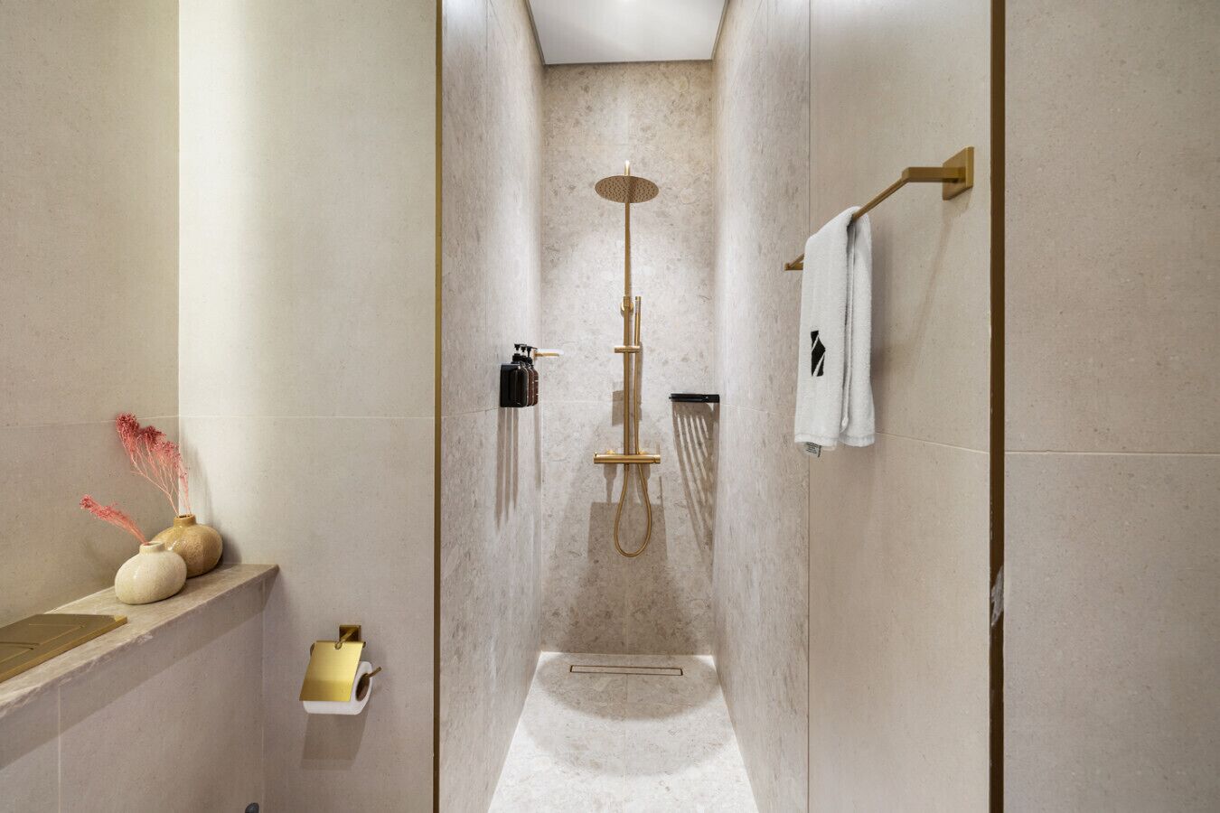 A modern bathroom with a walk-in shower, a towel rack, and a small shelf with decorative items.