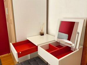 A compact room with a white desk, a red drawer, a mirror, and a small shelf with a reed diffuser. - Suite Apartment at Walking Distance to Sea in Alanya (Antalya)