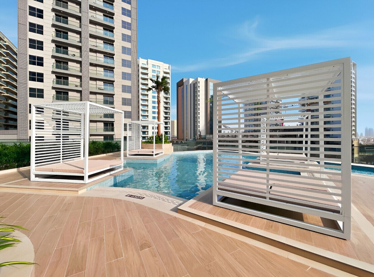 A rooftop swimming pool with white sunshade structures, surrounded by high-rise buildings.