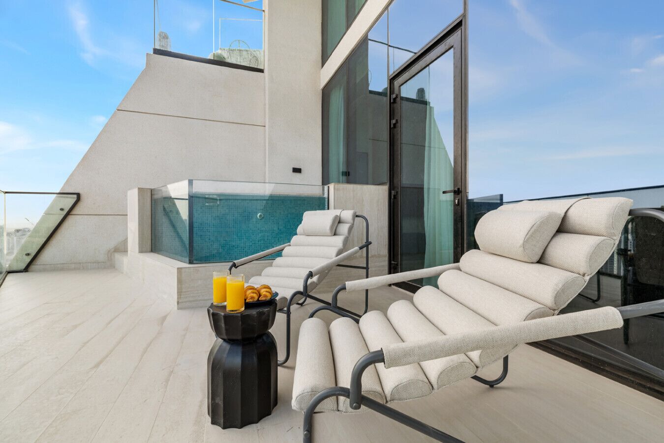 Eine Dachterrasse mit Pool, Liegestühlen und einem Tisch mit Getränken.
