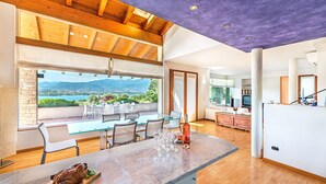 A spacious dining area with a large table, chairs, and a view of mountains.