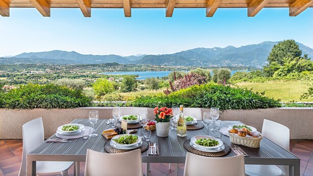 A table set for four with a scenic view of mountains and a lake.
