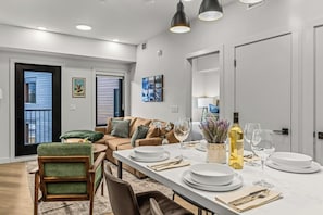 Een eetgedeelte met een lange tafel gedekt voor vier personen, een bank en uitzicht op het exterieur.