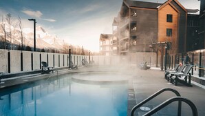 Ett poolområde med solstolar och en byggnad med flera balkonger.