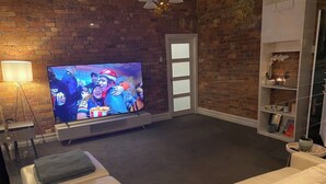 Una sala de estar con pared de ladrillo, un televisor de pantalla plana, un sofá y una mesa de centro.