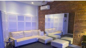 Una sala moderna con un sofá seccional, otomanas, una mesita auxiliar y un espejo grande.