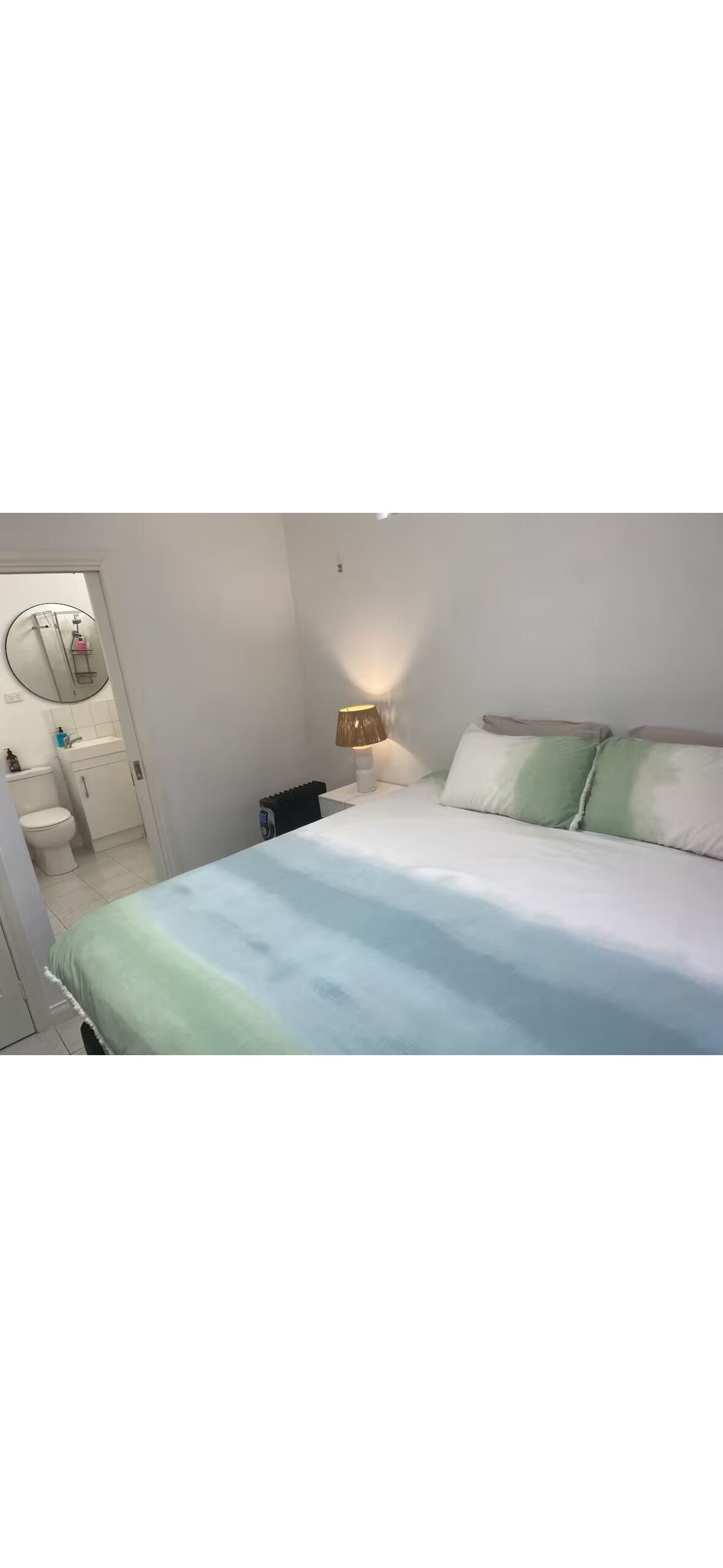 Une chambre à coucher avec un lit, une table de chevet, une lampe et un miroir.