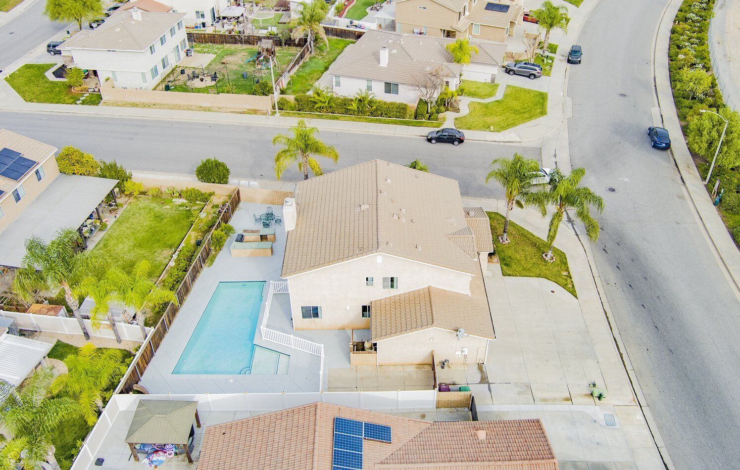 A residential area with a large house featuring a swimming pool, a garage, and a driveway.