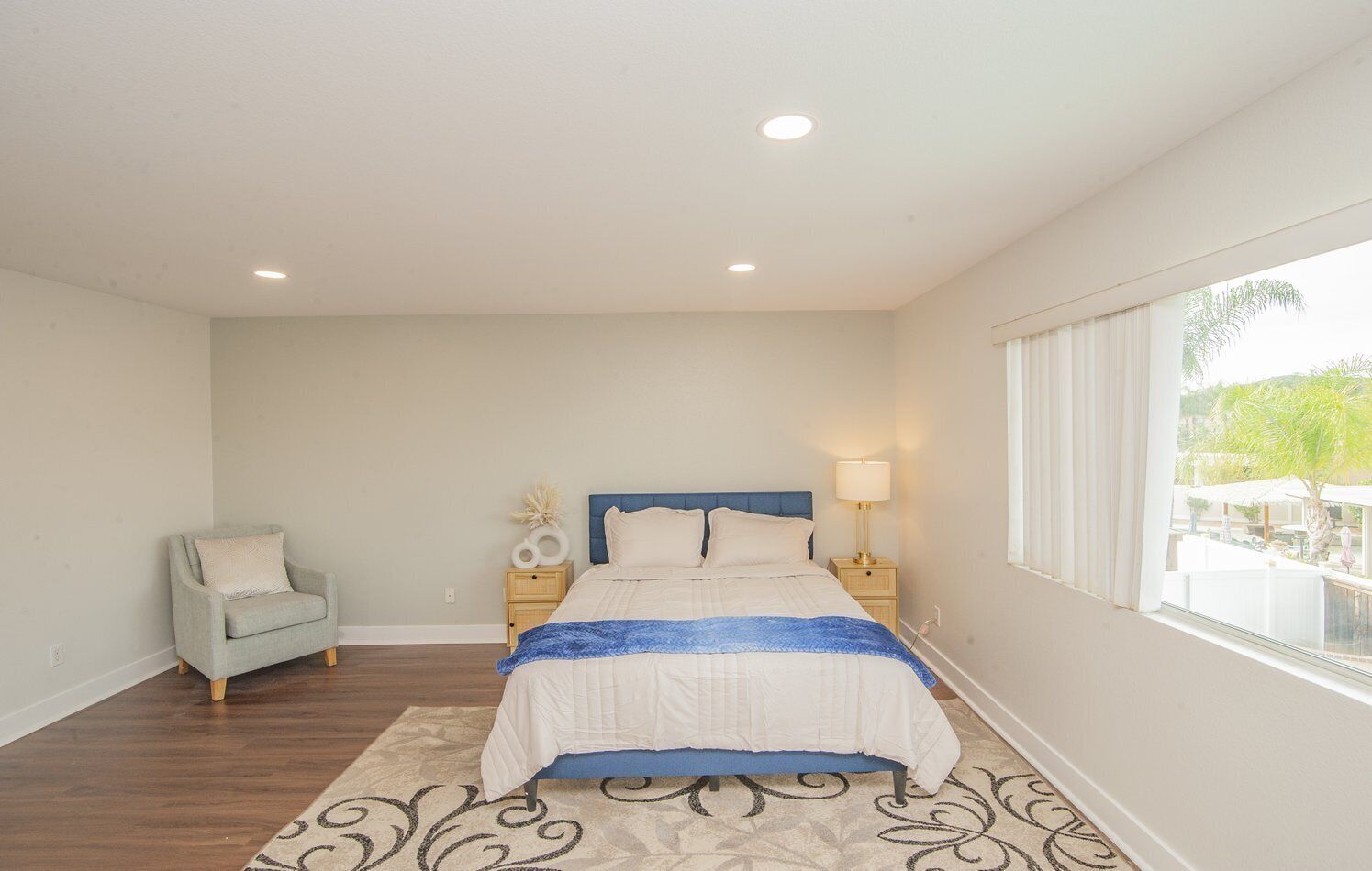 A bedroom with a bed, nightstands, a chair, and a window with a view.