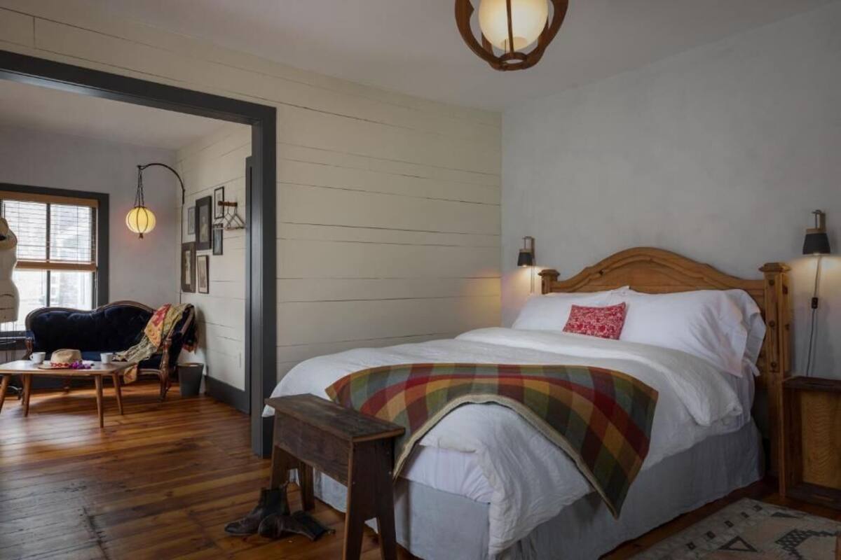 Una camera accogliente con un letto di legno, un comodino, una lampada, una finestra e una sedia.