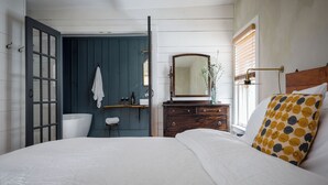 A bedroom with a bed, a dresser, a mirror, and a window with blinds. - Howland House (Mount Tremper)