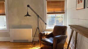 A room with a leather armchair, a floor lamp, and a radiator. - Howland House (Mount Tremper)
