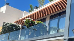 En modern byggnad med en balkong som har en träpergola och blomkrukor.