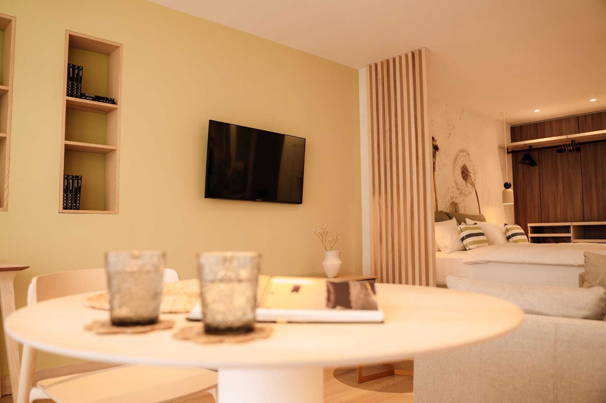 A modern living room with a round table, a flat-screen TV, and a sofa.