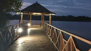 A wooden pier leading to a gazebo with a roof, surrounded by water and trees. - ASSINIE Oasis (Assinie)