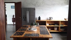 A modern kitchen with a marble backsplash, a central island with a tray, and a refrigerator. - ASSINIE Oasis (Assinie)