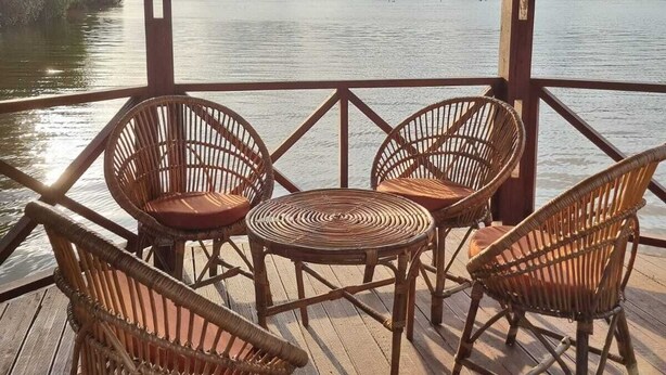 A wooden deck with wicker chairs and a table overlooking a lake. - ASSINIE Oasis (Assinie)