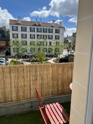 Un balcone con vista su un edificio, una recinzione e auto parcheggiate.