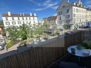 A courtyard with a wooden fence, a table with a cup and a plant, and buildings in the background. - Studio Saint-Germain-en-Laye -RER A- Near Paris (Saint-Germain-en-Laye)