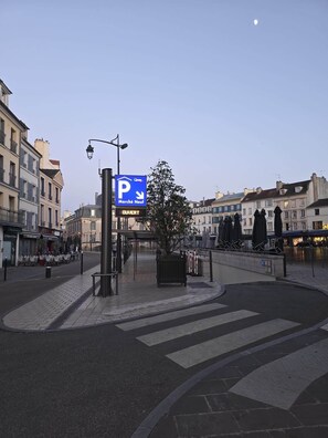 Kaupungin katu, jossa on sininen pysäköintikyltti, jalankulkijoiden suojatie ja taustalla näkyviä rakennuksia.