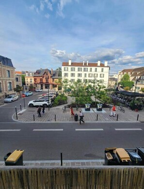 Una vista di strada con un edificio con diverse finestre, un'area di parcheggio e alcune persone che camminano.