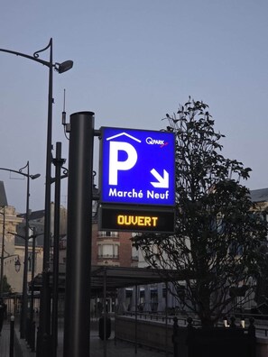 Sininen pysäköintikyltti, jossa lukee tekstiä «Q PARK» ja «Marché Neuf», sekä digitaalinen näyttö, jossa lukee «AVOIN».