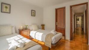 Une chambre d’hôtel avec deux lits, une porte en bois et un couloir menant à une salle à manger.