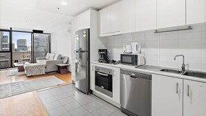 Een moderne keuken met roestvrijstalen apparatuur, witte kasten en een groot raam met uitzicht over de stad.