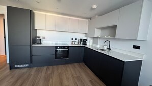Una cocina moderna con horno empotrado, un lavamanos y una cafetera.