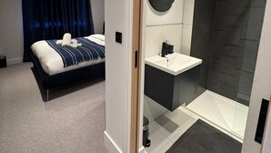 Habitación de hotel moderna con cama, baño con ducha y un lavamanos pequeño.