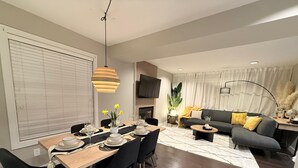 Un salon moderne avec un coin repas, comprenant un canapé, une table basse et une table à manger pour quatre personnes.