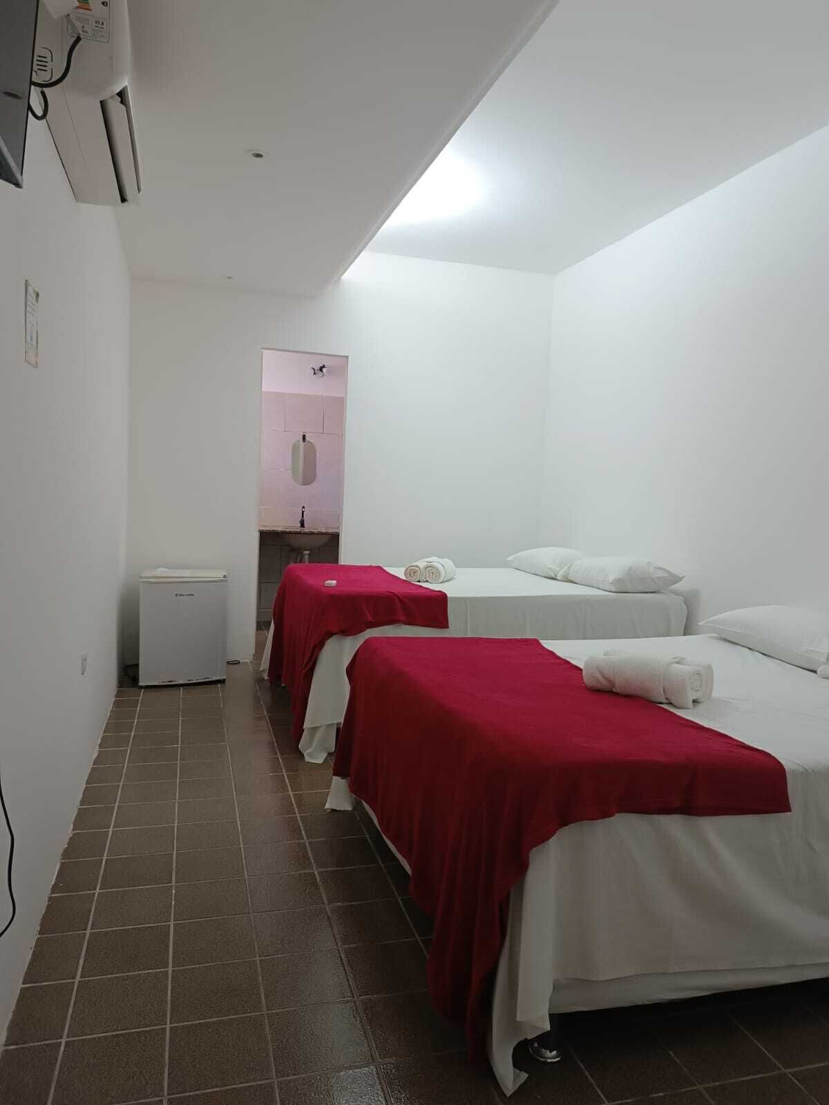 A hotel room with two beds, a small kitchenette, and a bathroom visible through a door.