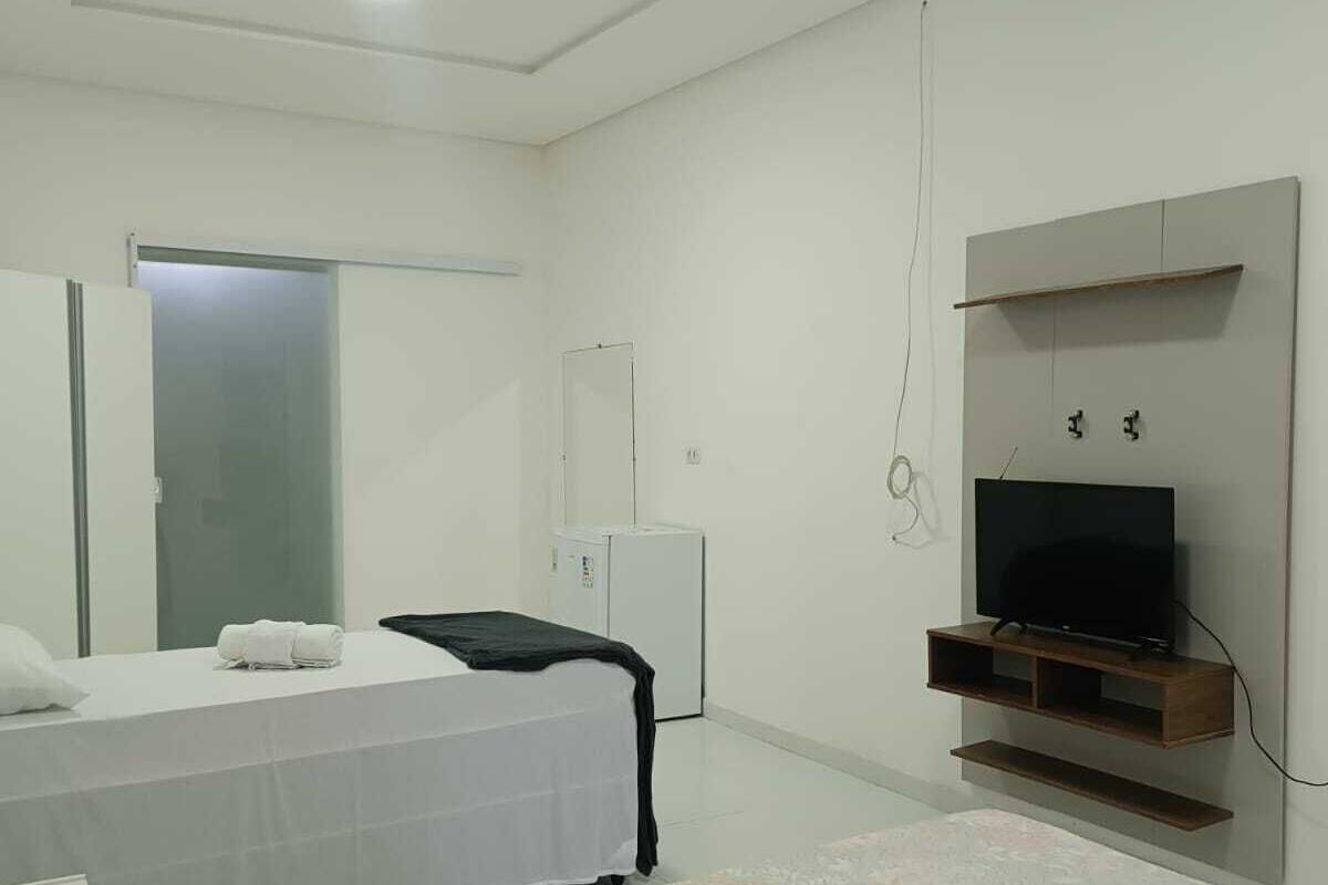 Une chambre à coucher moderne, équipée d’un lit, d’une télévision, d’une armoire et d’une porte.