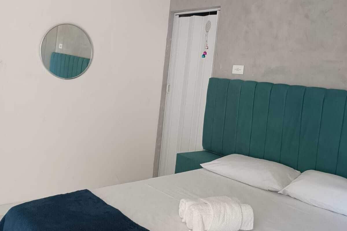 Une chambre à coucher avec un lit, un miroir rond, une porte et un luminaire blanc au plafond.